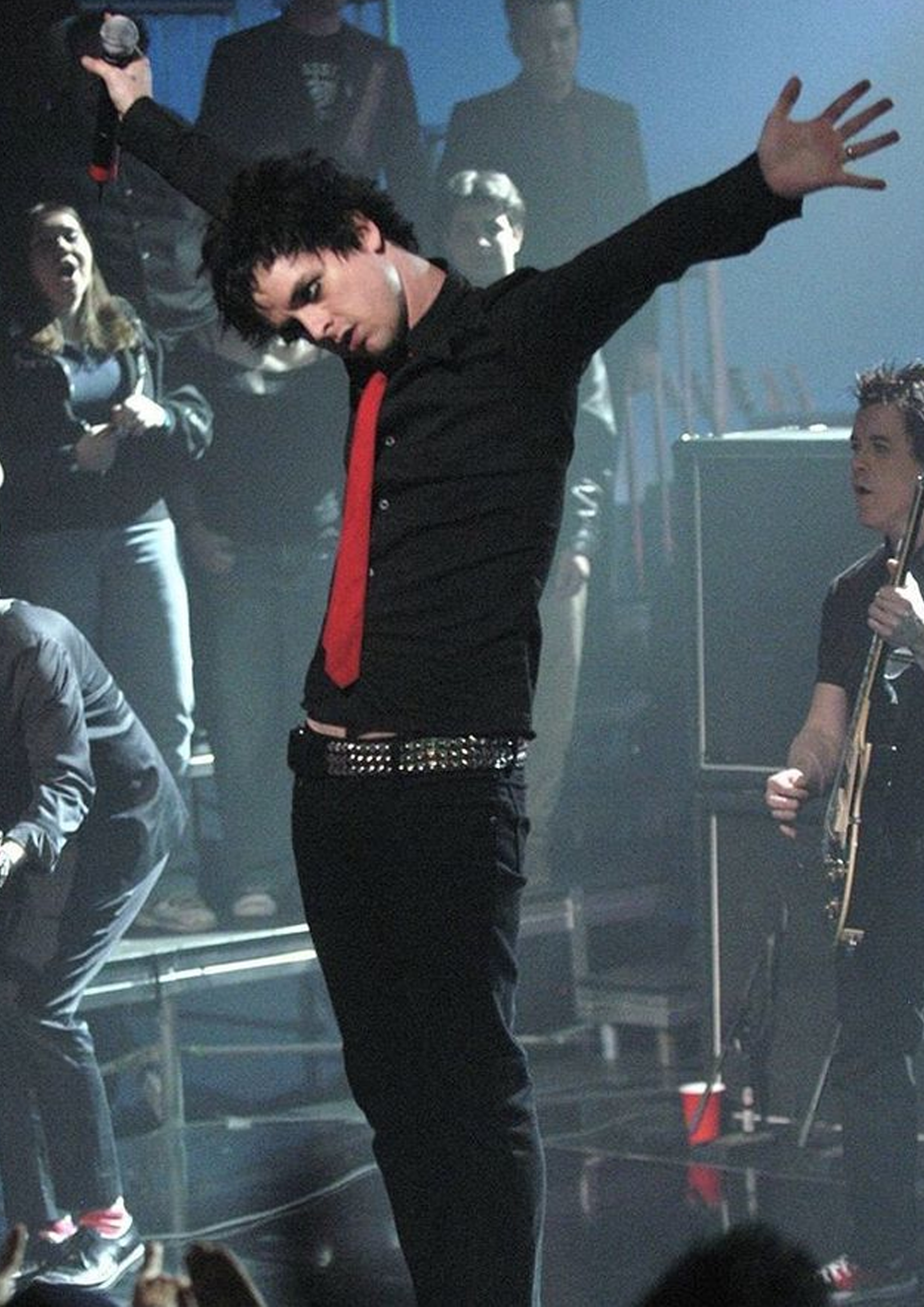 Before image: Billie Joe Armstrong from Green Day standing on stage with his arms out and slightly up.